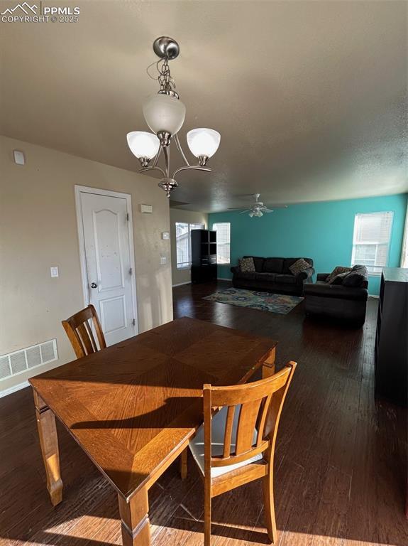 dining room with hardwood / wood-style floors and ceiling fan with notable chandelier