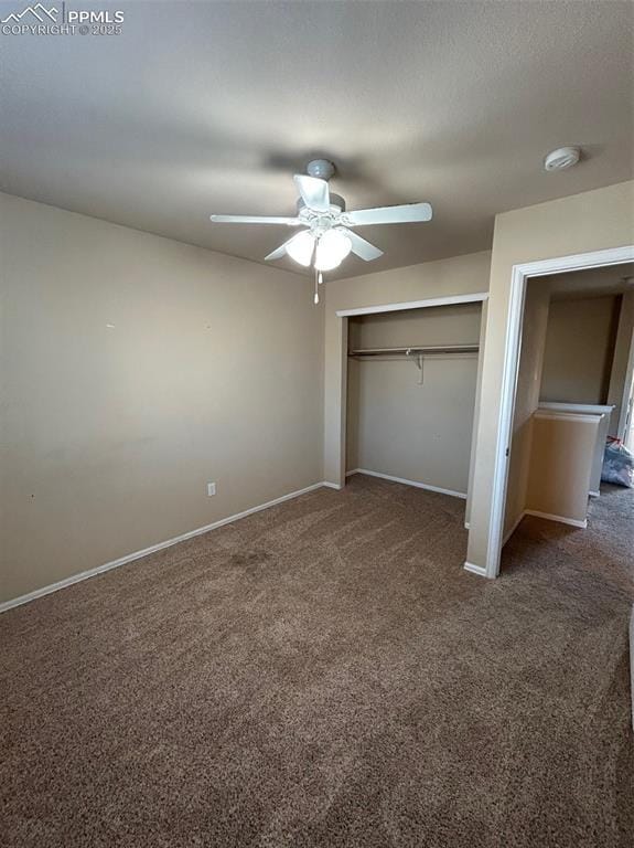 unfurnished bedroom with dark colored carpet, ceiling fan, and a closet