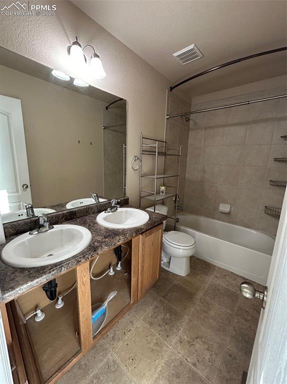 full bathroom with vanity, tiled shower / bath combo, and toilet