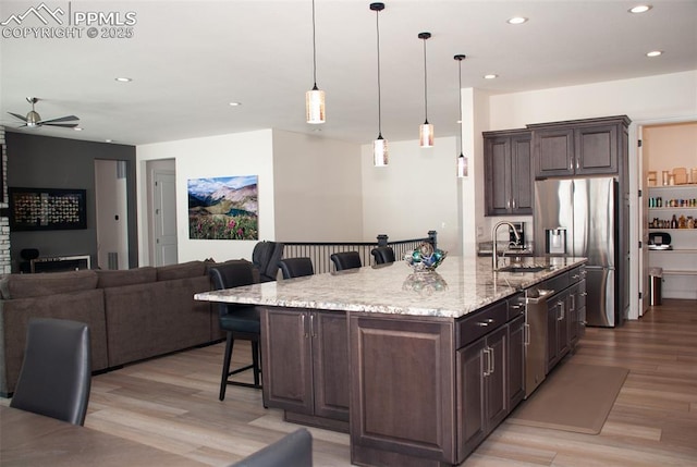 kitchen with a kitchen breakfast bar, dark brown cabinets, a spacious island, and stainless steel appliances