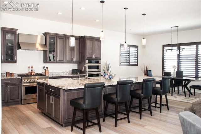 kitchen with a kitchen island with sink, dark brown cabinets, stainless steel appliances, and sink