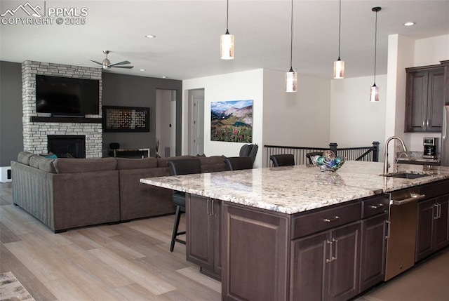 kitchen featuring a breakfast bar, dark brown cabinets, pendant lighting, and a center island with sink