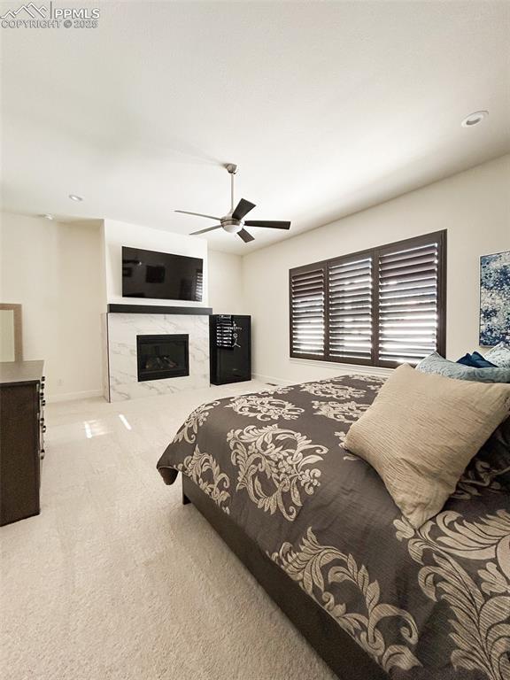 bedroom with a fireplace, light colored carpet, and ceiling fan