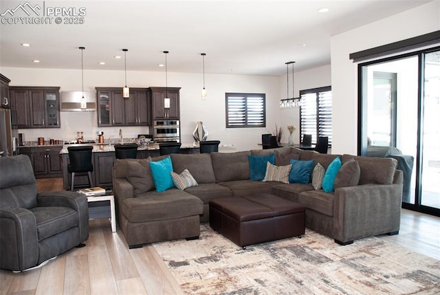 living room featuring light hardwood / wood-style floors, an inviting chandelier, and sink