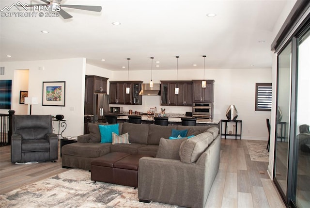 living room featuring ceiling fan, plenty of natural light, sink, and light hardwood / wood-style flooring