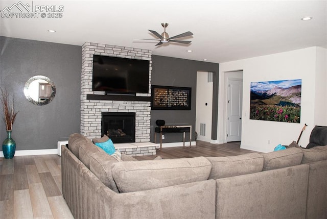 living room featuring hardwood / wood-style flooring, ceiling fan, and a brick fireplace