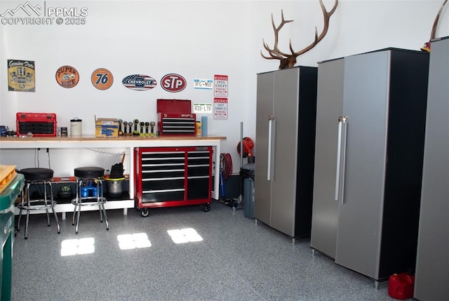 garage with stainless steel refrigerator and a workshop area