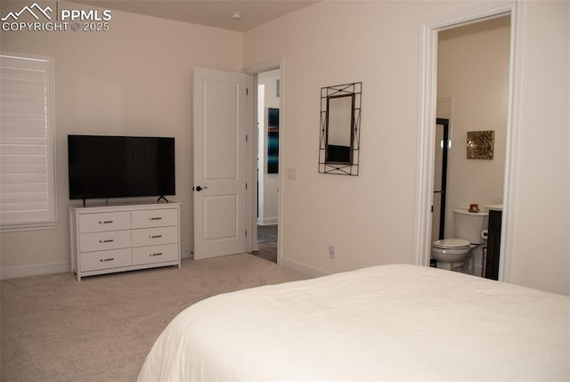 bedroom featuring connected bathroom and light colored carpet