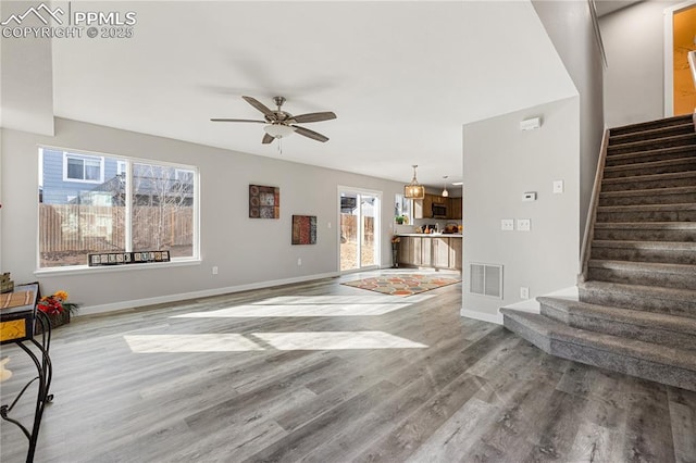 unfurnished living room featuring wood-type flooring and ceiling fan with notable chandelier