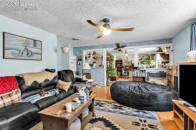 living room with ceiling fan, wood-type flooring, and a textured ceiling