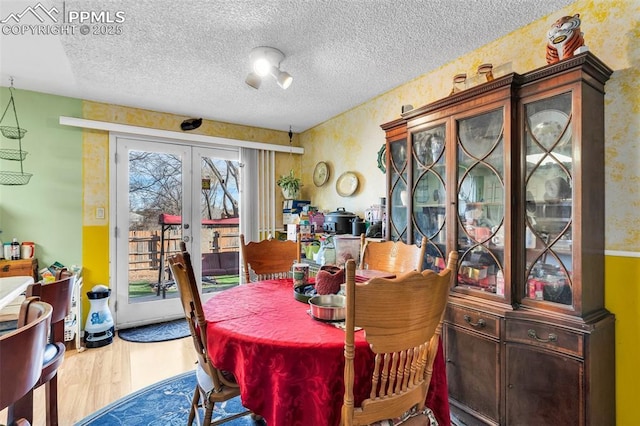 dining area with hardwood / wood-style floors, a textured ceiling, and french doors