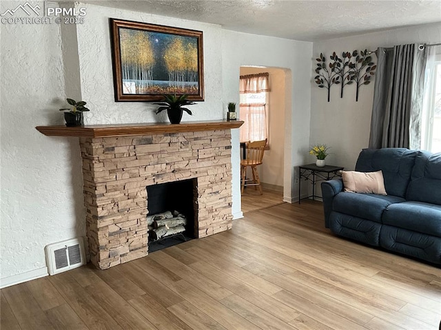 living room featuring a textured ceiling, a fireplace, and light hardwood / wood-style floors