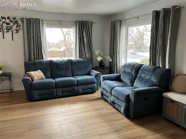 living room featuring light hardwood / wood-style flooring, a wealth of natural light, and a textured ceiling