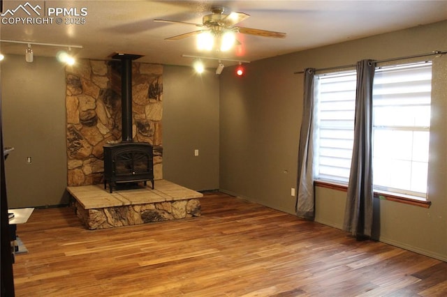 living room featuring hardwood / wood-style flooring, ceiling fan, a wood stove, and rail lighting