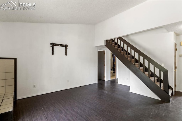 unfurnished living room with a textured ceiling and dark hardwood / wood-style floors