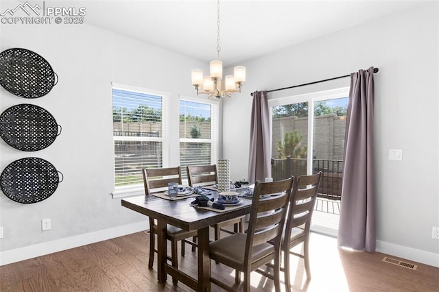 dining area with hardwood / wood-style flooring and an inviting chandelier