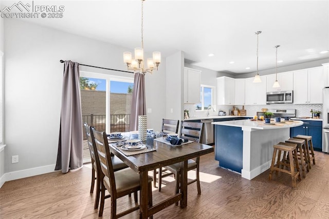 dining space with a chandelier, sink, and wood-type flooring