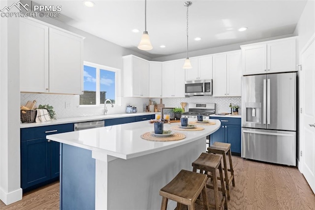 kitchen featuring light wood-type flooring, appliances with stainless steel finishes, a center island, and blue cabinets