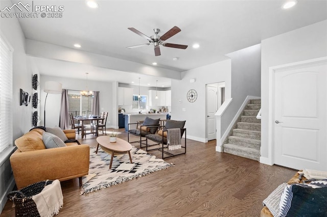 living room featuring ceiling fan with notable chandelier and dark hardwood / wood-style floors