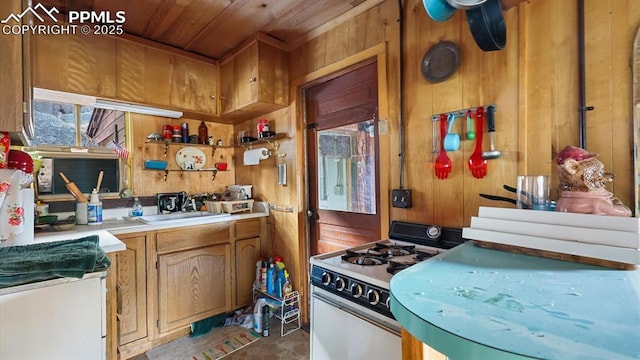 kitchen with sink, wood ceiling, white range with gas cooktop, and wood walls