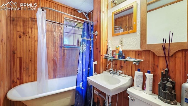 full bathroom with sink, toilet, shower / bathtub combination with curtain, and wood walls