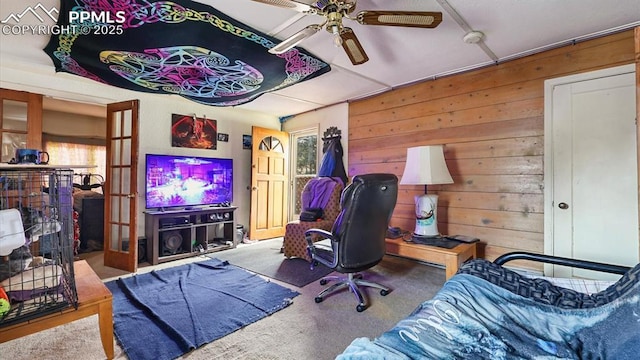 office space with carpet, ceiling fan, and wooden walls