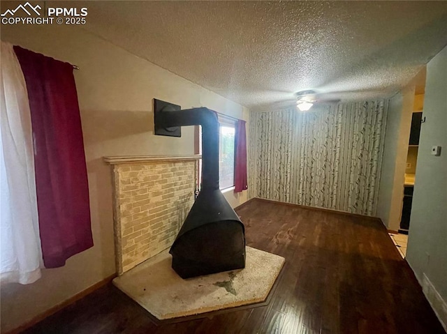 living room featuring a wood stove, ceiling fan, a textured ceiling, and hardwood / wood-style flooring