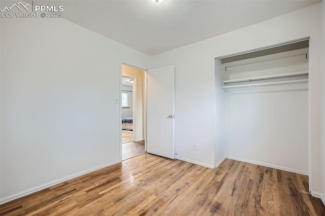 unfurnished bedroom with light hardwood / wood-style floors, a textured ceiling, and a closet