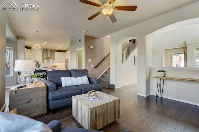 living room featuring ceiling fan with notable chandelier and dark hardwood / wood-style flooring