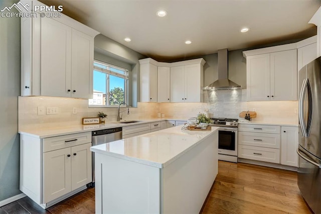 kitchen with white cabinets, wall chimney exhaust hood, stainless steel appliances, and a center island