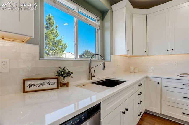 kitchen with white cabinets, backsplash, sink, and light stone counters