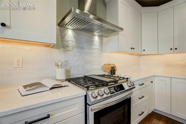 kitchen featuring backsplash, wall chimney range hood, stainless steel range with gas stovetop, white cabinetry, and light stone countertops