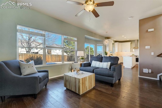 living room with dark hardwood / wood-style flooring and ceiling fan with notable chandelier