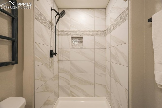 bathroom featuring toilet and a tile shower