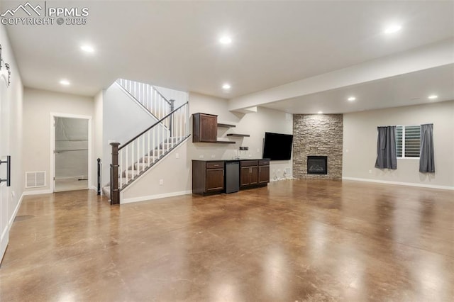 unfurnished living room featuring a stone fireplace and concrete flooring