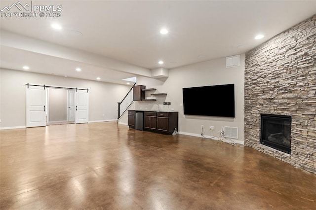 unfurnished living room featuring a barn door, concrete flooring, and a fireplace