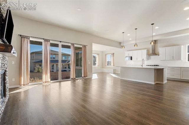 unfurnished living room with hardwood / wood-style flooring and a stone fireplace