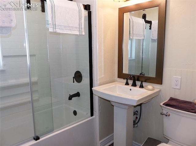 bathroom featuring toilet and bath / shower combo with glass door