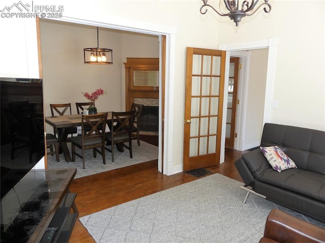 living room featuring a chandelier, wood-type flooring, and a stone fireplace