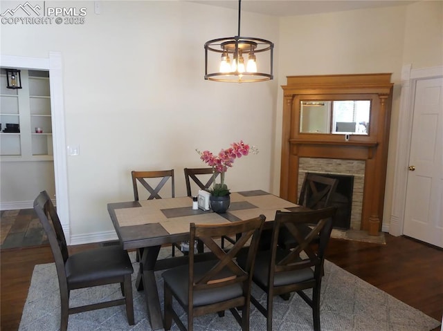 dining space with a notable chandelier, dark hardwood / wood-style floors, and a fireplace