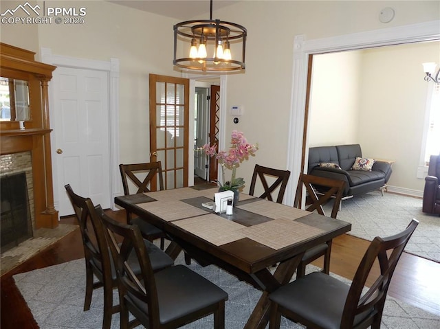 dining room featuring light hardwood / wood-style floors, a brick fireplace, and a notable chandelier