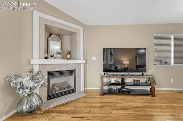 living room with hardwood / wood-style floors and a tiled fireplace