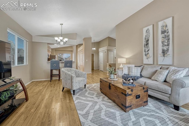 living room with hardwood / wood-style floors, vaulted ceiling, and a chandelier