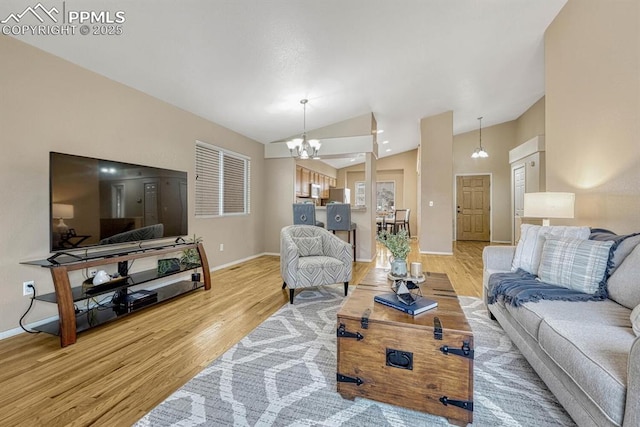 living room featuring a chandelier, light wood-type flooring, and vaulted ceiling