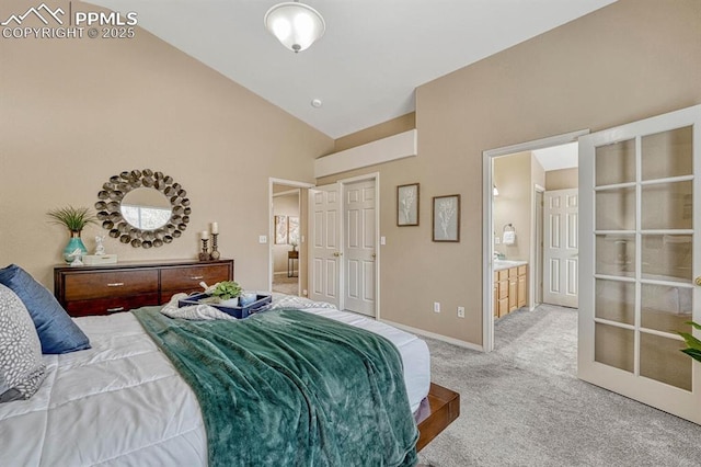 bedroom with ensuite bathroom, carpet floors, and high vaulted ceiling