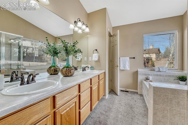 bathroom featuring vanity, tiled tub, and vaulted ceiling