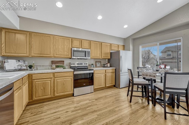 kitchen with sink, light hardwood / wood-style floors, lofted ceiling, light brown cabinetry, and appliances with stainless steel finishes