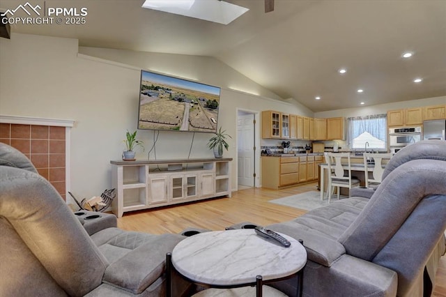 living area featuring vaulted ceiling with skylight, light wood-style flooring, and recessed lighting