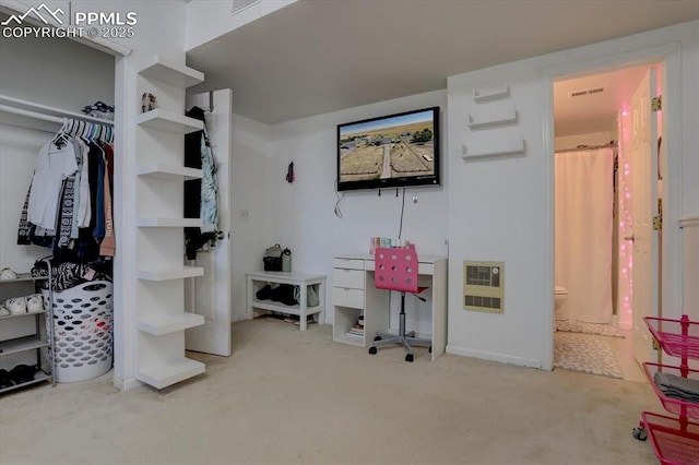 carpeted bedroom with connected bathroom, visible vents, and heating unit