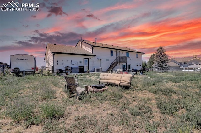 rear view of property featuring stairway, an outdoor fire pit, and fence